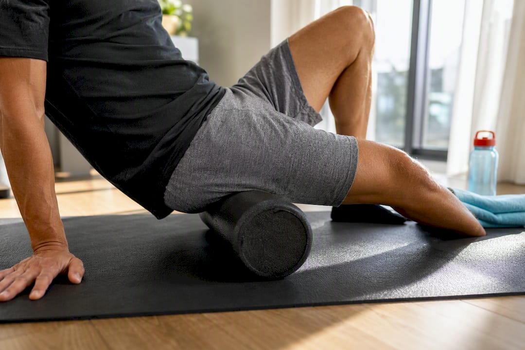 Athlete using foam roller on outer thigh